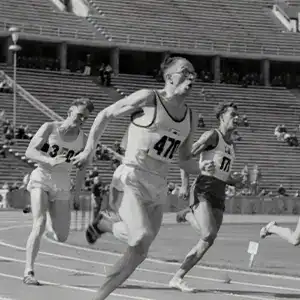Vintage track and field race with athletes running on a stadium track.